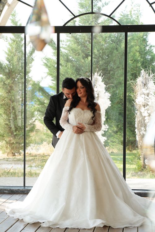 Free Beautiful couple in wedding attire posing indoors by large windows. Stock Photo