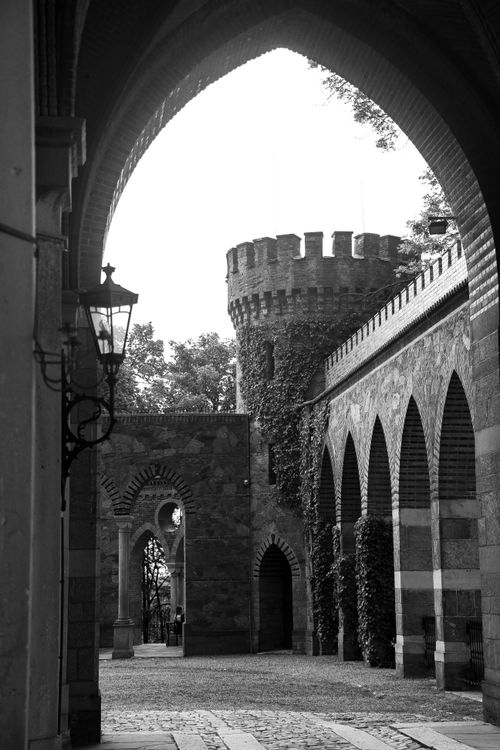Free Black and white image of a stone fortress with gothic arches and a turreted tower. Stock Photo