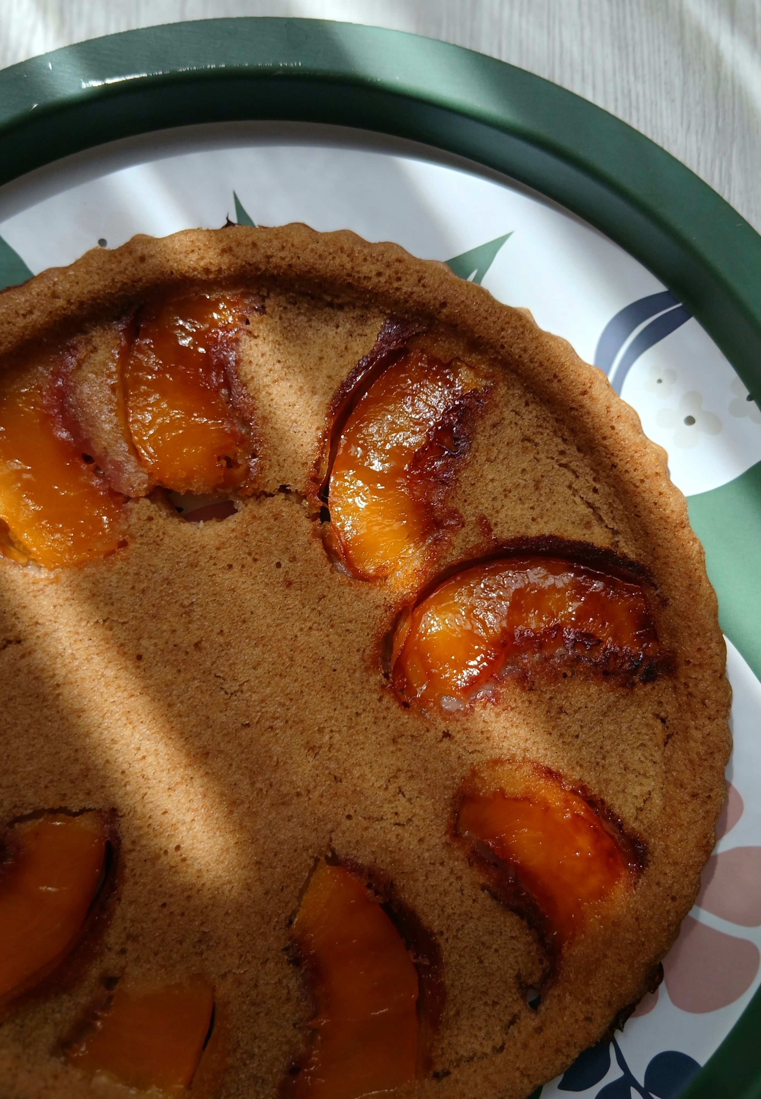 A golden lattice-top peach pie on a wire cooling rack, thick amber peach juices bubbling up through the woven crust.