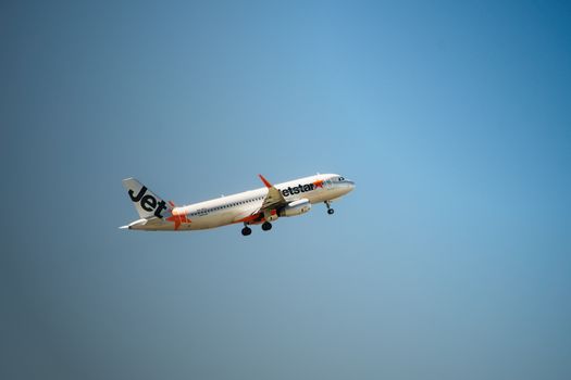 Jetstar airplane flying mid-air with clear blue sky backdrop