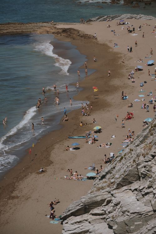 Free Sunbathers enjoy the summer sun on a crowded San Sebastián beach in Spain. Stock Photo
