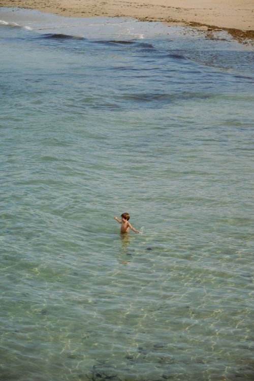 Free A child playing in the clear waters of La Concha Beach in San Sebastián, capturing the essence of summer leisure. Stock Photo