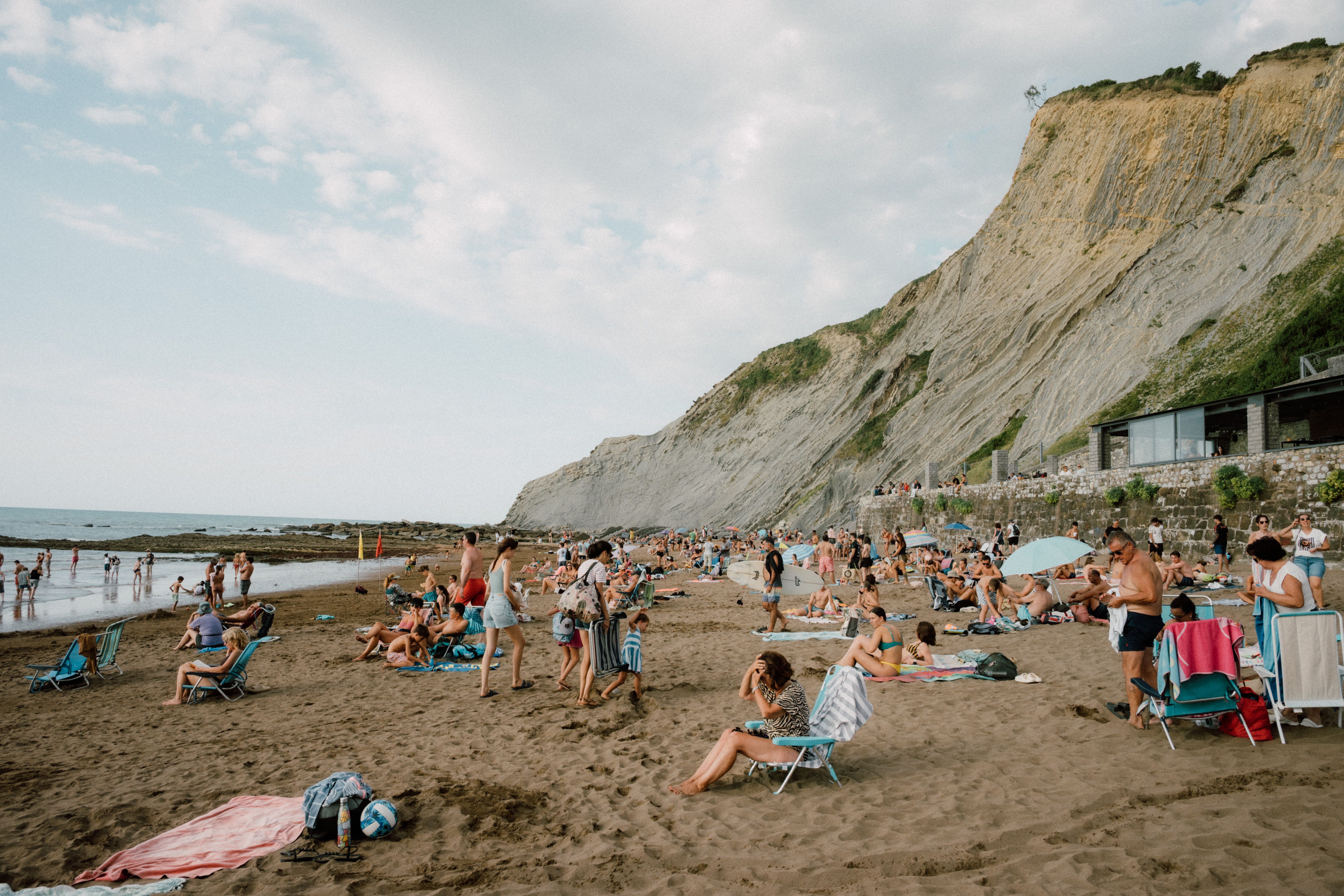 Crowded summer scene at a sandy beach in Donostia, Spain with people enjoying the sun and sea.