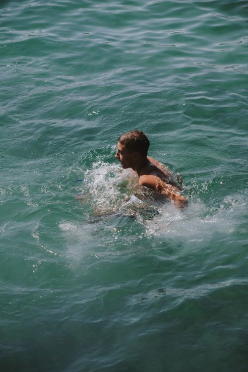Free A man swimming in clear waters of San Sebastián, enjoying a refreshing summer dip. Stock Photo
