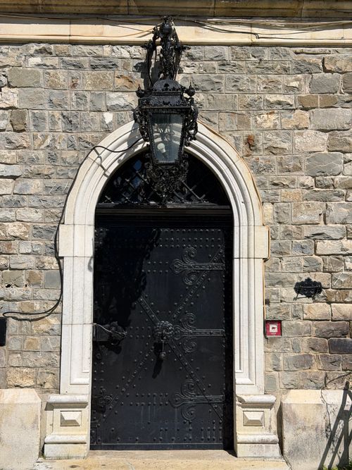 Free Stone wall with an ornate Gothic doorway in Sinaia, featuring intricate ironwork and architecture. Stock Photo