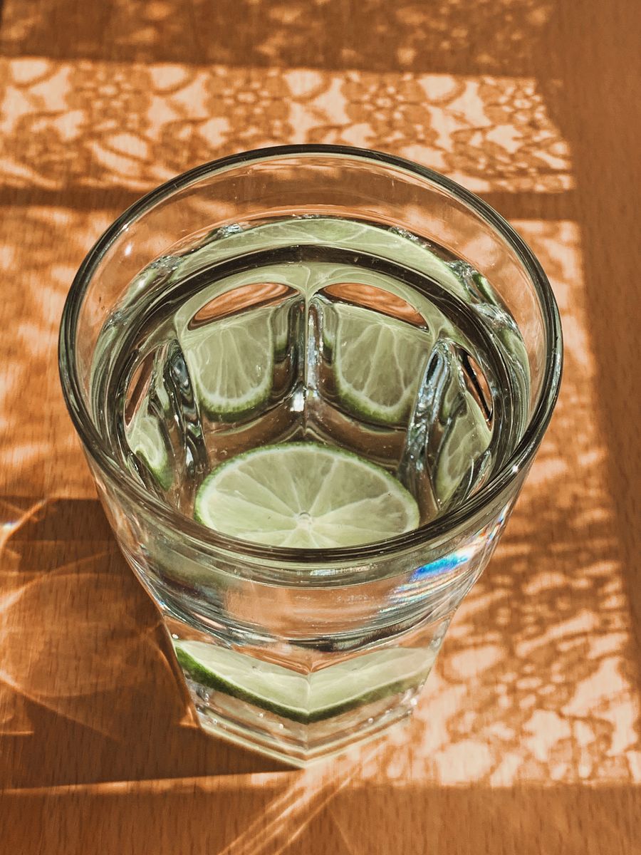 A glass of water with lime slices in warm sunlight