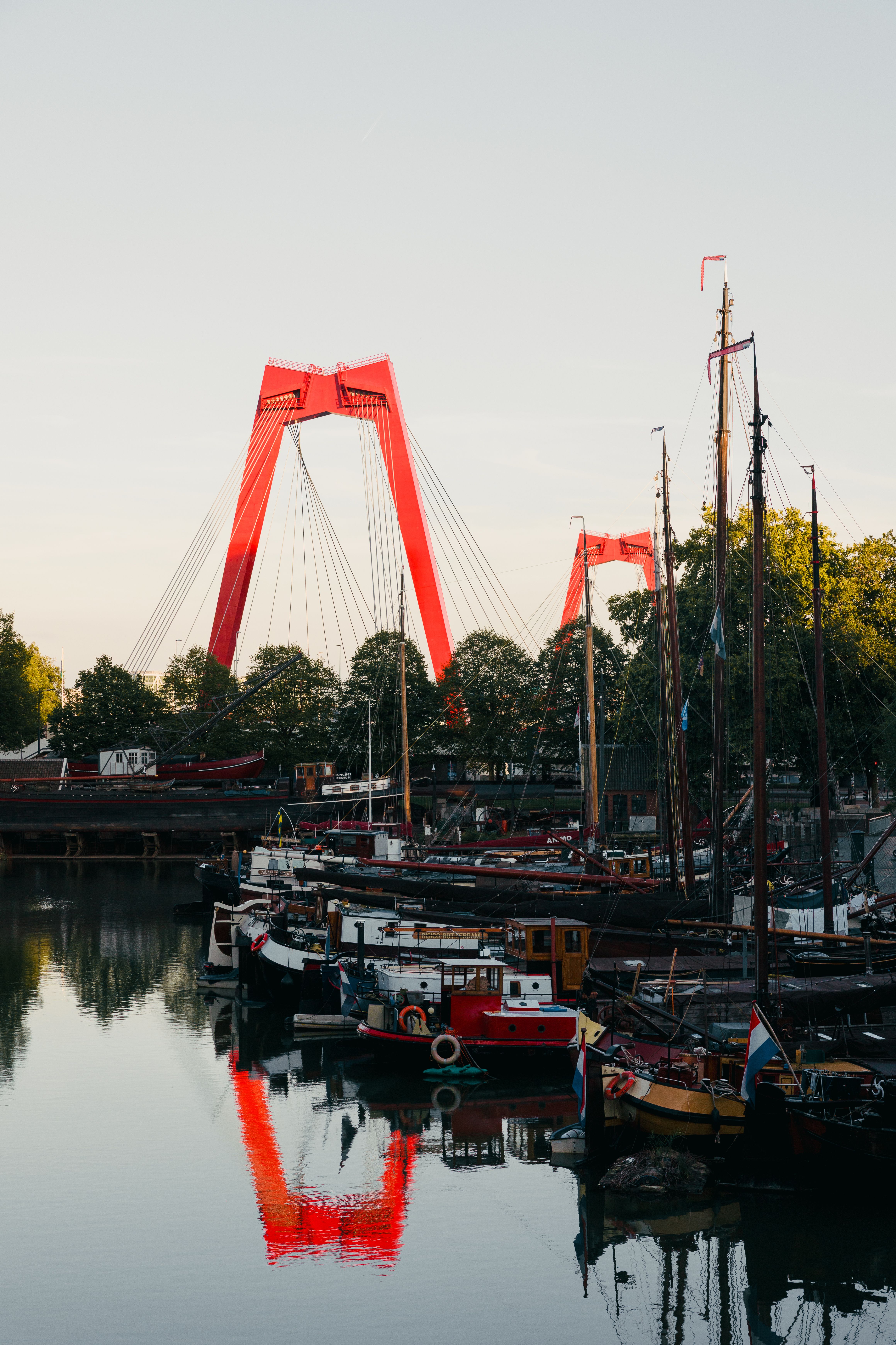 View of the iconic Willemsbrug with boats in Rotterdam harbor during the day.