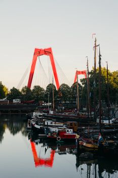 View of the iconic Willemsbrug with boats in Rotterdam harbor during the day.