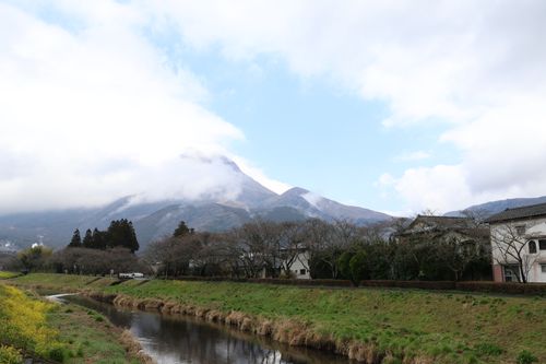 Free A tranquil landscape with a misty mountain, serene stream, and countryside houses. Stock Photo
