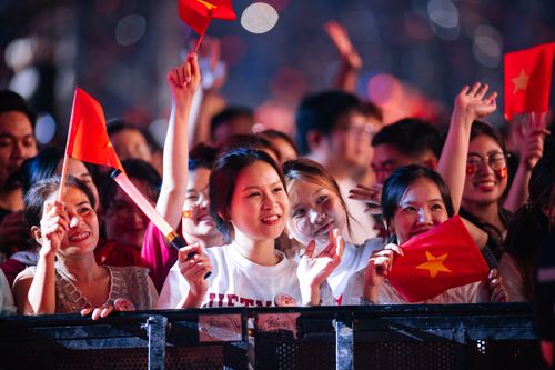 Free A lively group of adults waving red flags at a nighttime celebration. Stock Photo