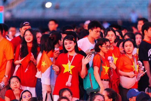 Free Cheerful Vietnamese fans in vibrant outfits wave flags during a lively outdoor event. Stock Photo