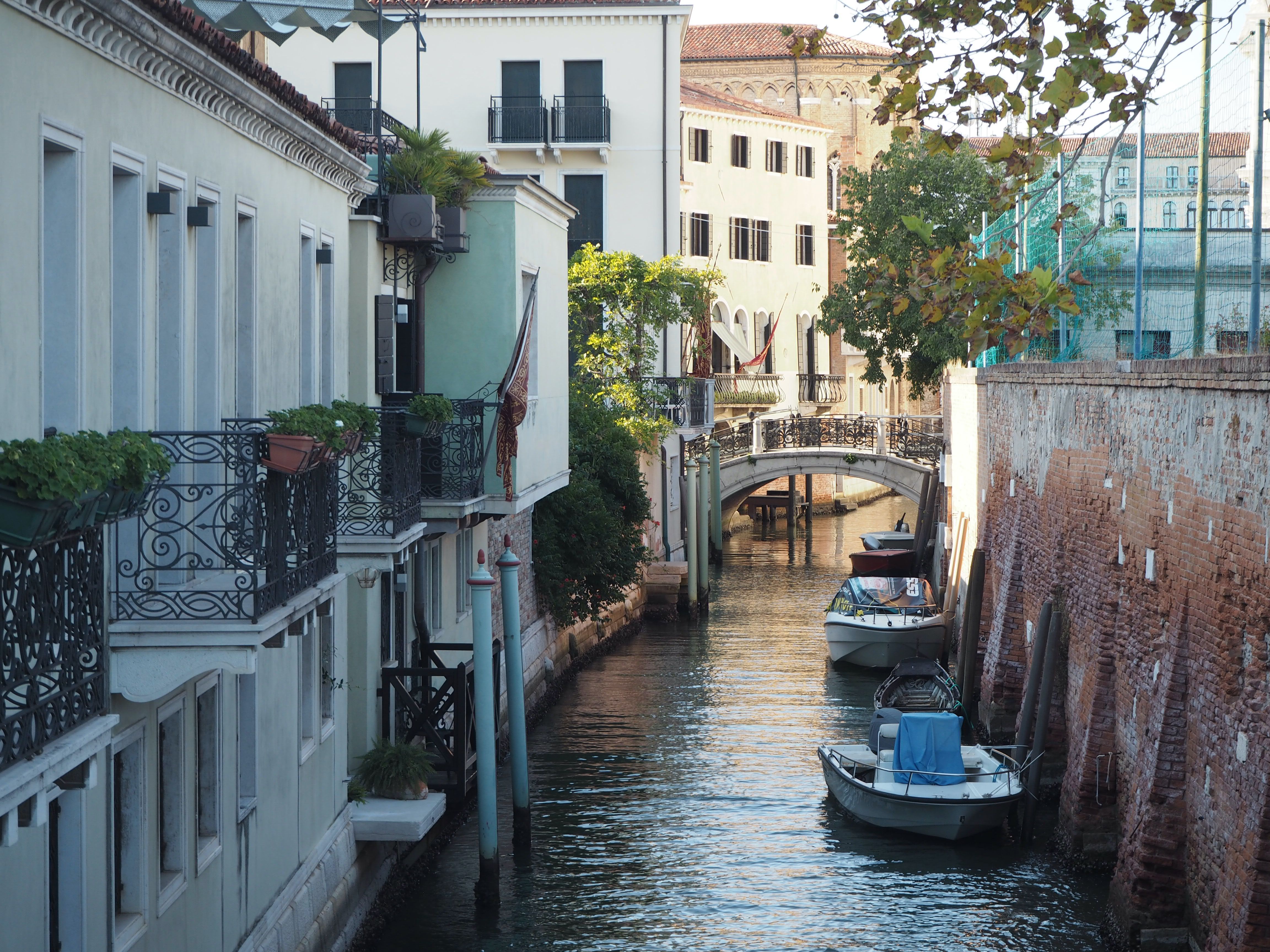 Picturesque view of a canal street with boats and bridge in Venice, Italy.