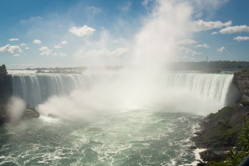 Free A stunning capture of Niagara Falls showcasing powerful waterfalls and mist under a sunny sky. Stock Photo