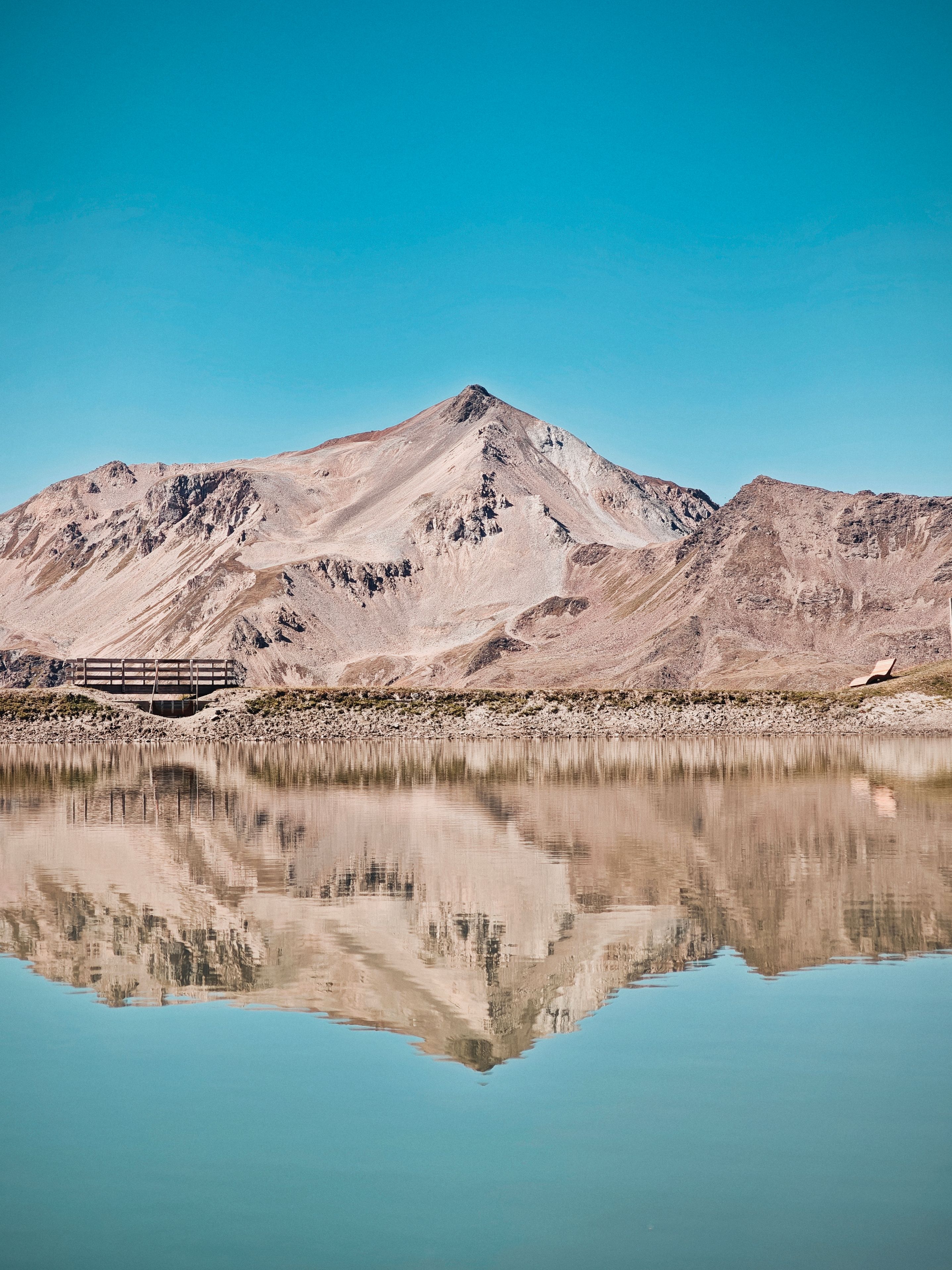 Stunning mountain reflected in a calm lake under a clear blue sky.