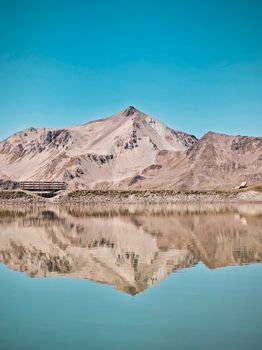 Stunning mountain reflected in a calm lake under a clear blue sky.