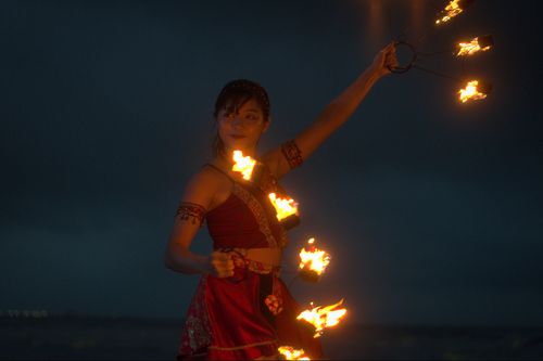 Free A woman performing fire dance on a beach during nighttime under a dark sky. Stock Photo