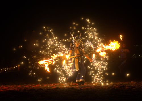 Free A dramatic fire performer in costume creates a dazzling display of flames and sparks at night. Stock Photo