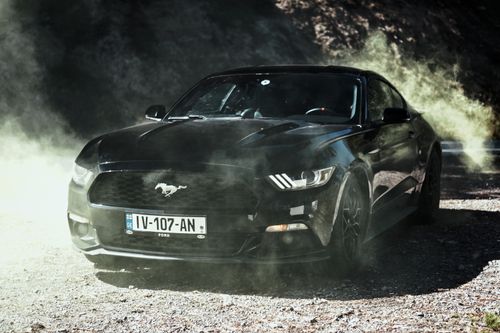 Free A sleek black sports car engulfed in dust, emphasizing power and dynamic movement. Stock Photo