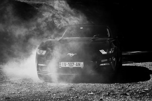Free A striking black and white image of a car surrounded by dramatic smoke in a mysterious outdoor setting. Stock Photo