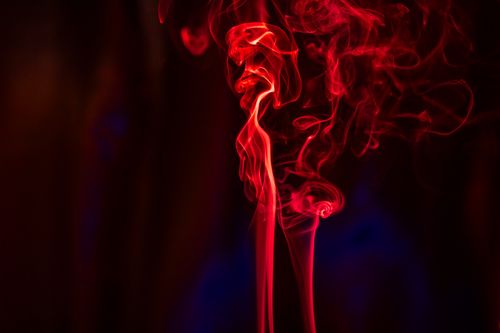 Free Vivid red smoke swirling gracefully against a dark background, creating an abstract and ethereal effect. Stock Photo