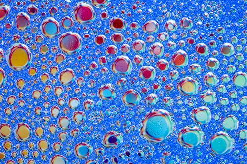 Free Vivid soap bubbles form a colorful abstract pattern against a blue background. Perfect for creative projects. Stock Photo