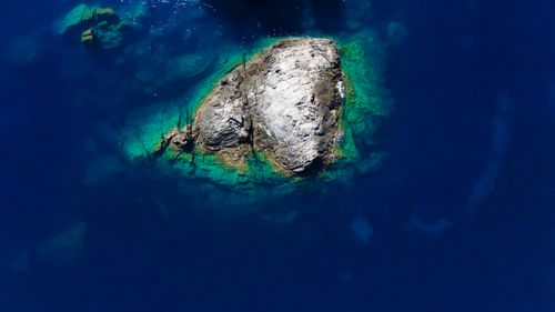 Free Stunning aerial view of a rocky island surrounded by deep blue waters in Greece. Stock Photo