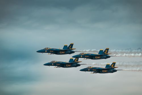 Free Four U.S. Navy Blue Angels jets in precise aerial formation against a cloudy sky. Stock Photo