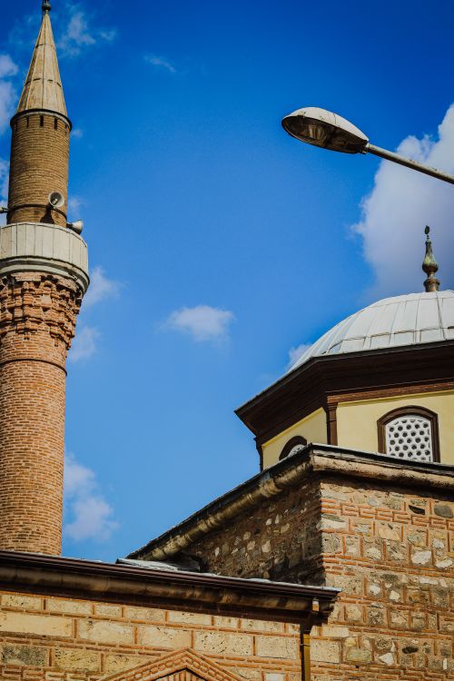 Free A striking view of a historical minaret and dome against a vibrant blue sky in Bursa, Türkiye. Stock Photo
