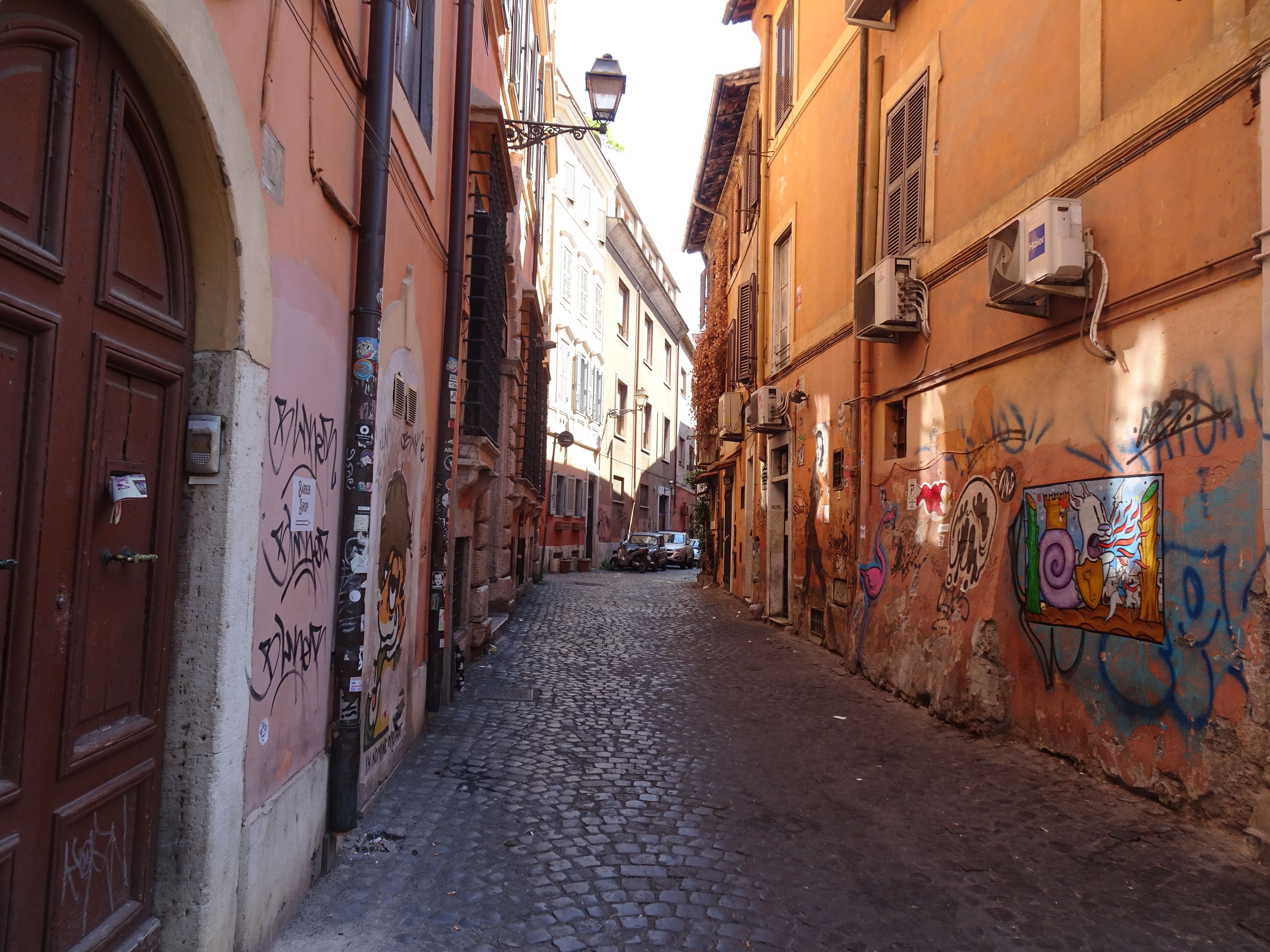 Discover a vibrant alley in Rome, showcasing colorful graffiti on classic architecture.