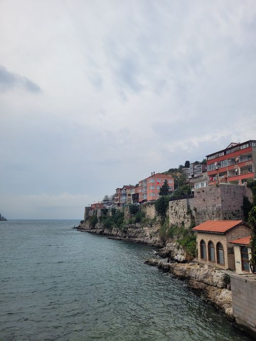 Free Picturesque seaside cliff with colorful buildings under a cloudy sky. Serene coastal landscape. Stock Photo
