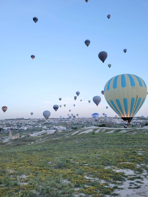 Free Colorful hot air balloons soar above the unique landscape of Cappadocia, Turkey at sunrise. Stock Photo