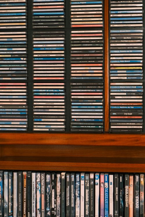 Free A neatly arranged collection of CDs displayed on a wooden shelf, showcasing various music genres. Stock Photo