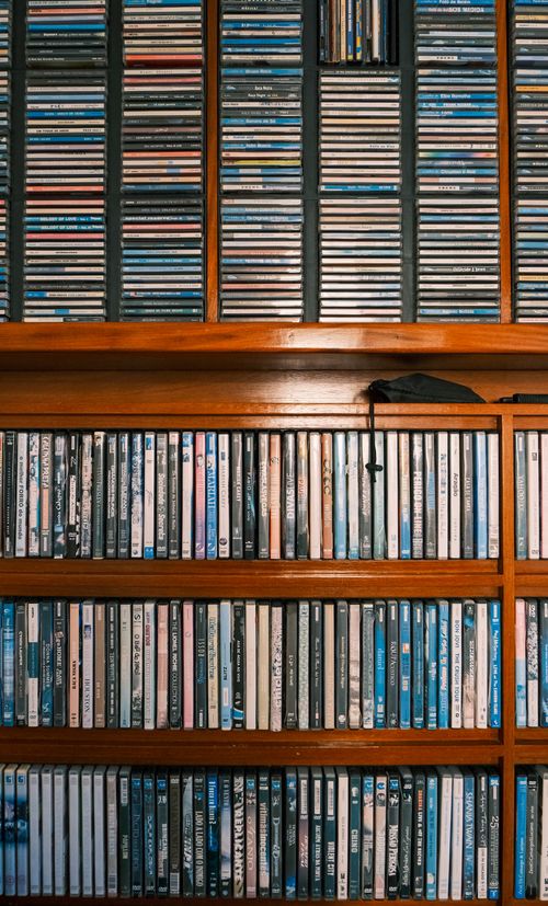 Free A neatly arranged collection of CDs on wooden shelves displaying various album covers. Stock Photo