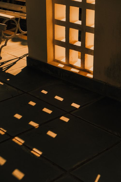 Free Intriguing interplay of sunlight and shadows through architectural grid window. Stock Photo