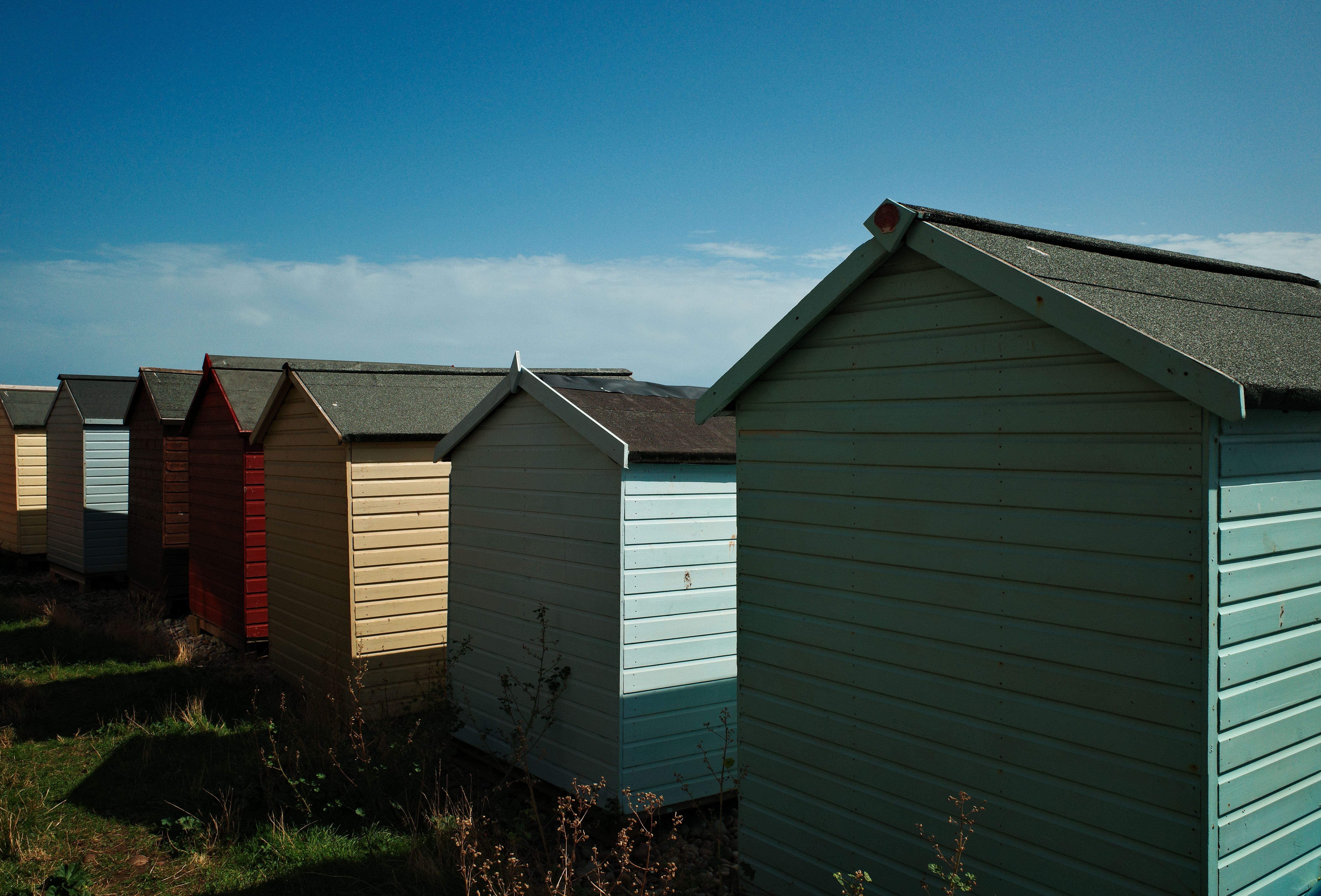 Row of vibrant beach huts in a coastal setting under a bright blue sky.