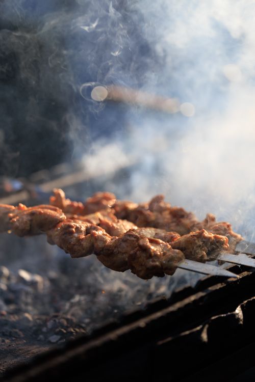Free Close-up of skewered meat cooking on a grill with smoke. Captured in Kaliningrad, Russia. Stock Photo