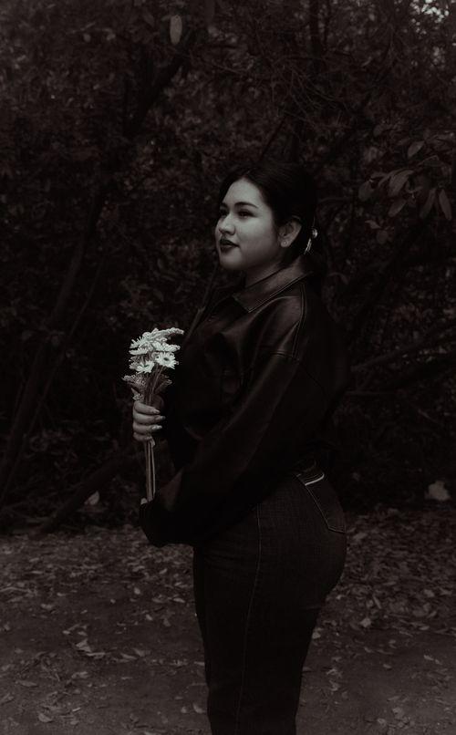 Free A monochrome portrait of a woman holding a bouquet of flowers in a natural setting. Stock Photo