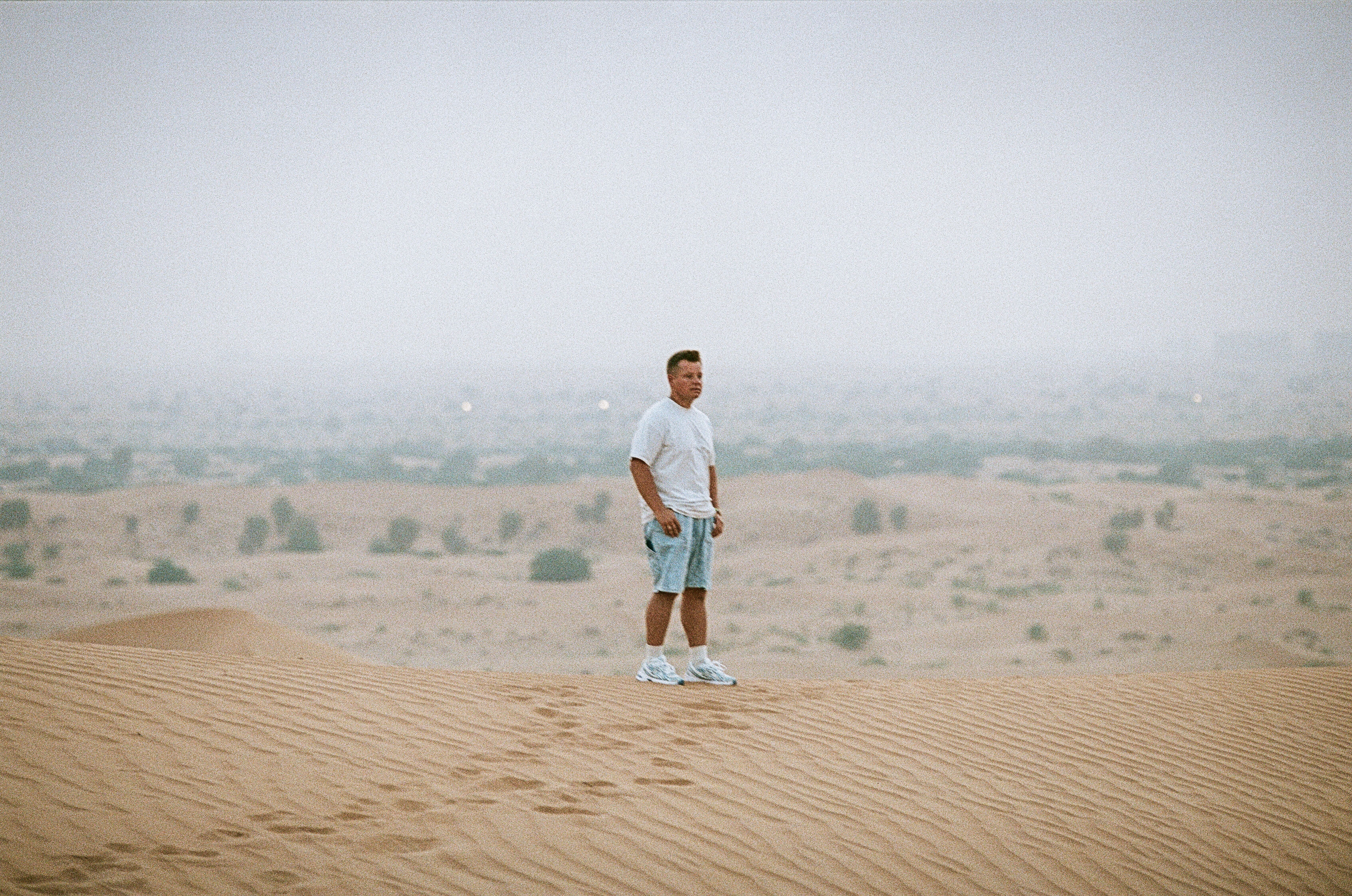 A person standing alone on a sand dune in the vast Ras Al-Khaimah desert, UAE.