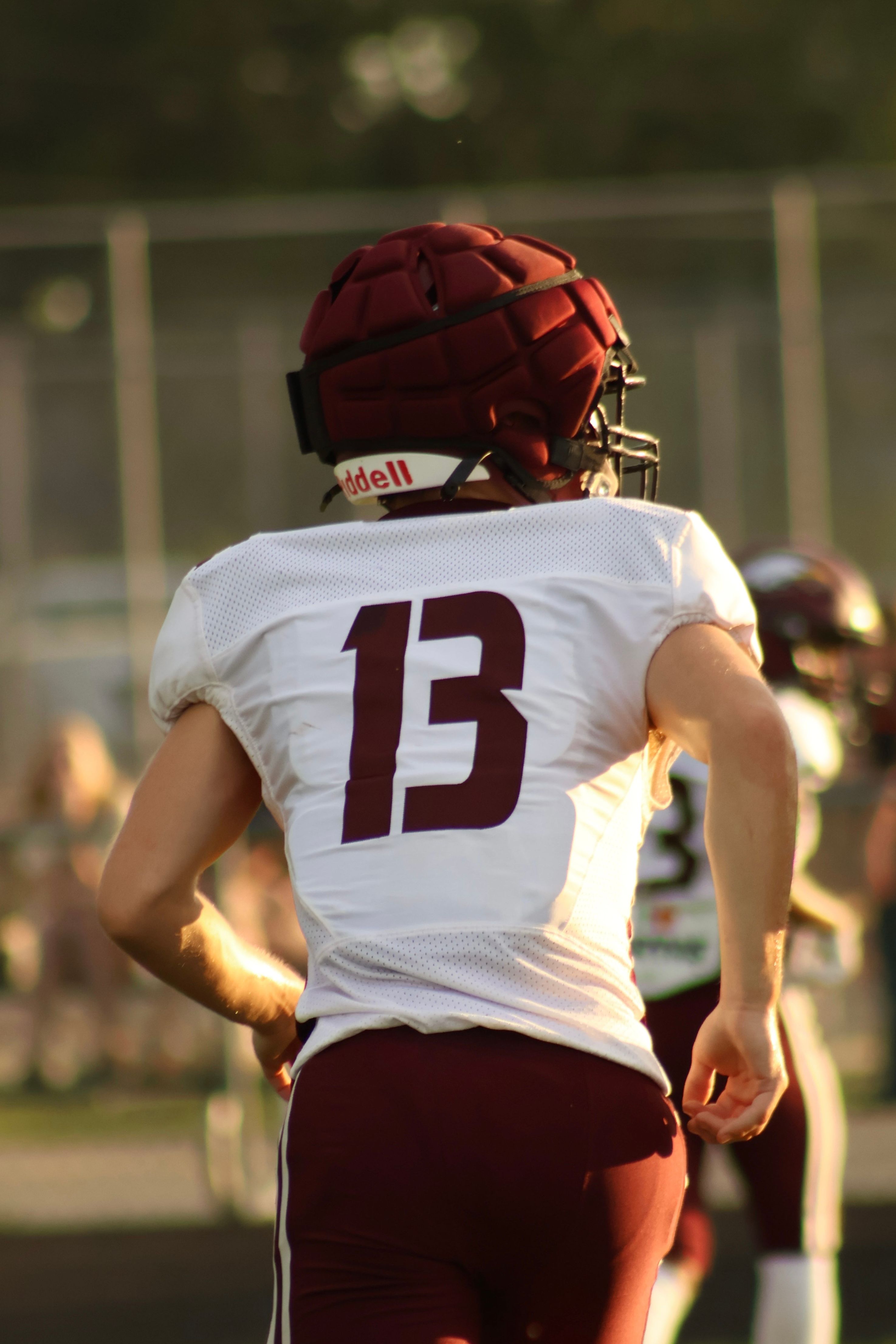 Rear view of a football player in a maroon uniform running during a game.