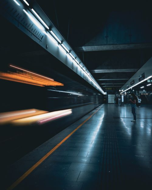 Free Blurred motion of a subway train at night with a lone passenger on the platform. Urban transit atmosphere. Stock Photo