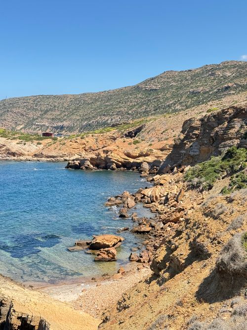 Free Beautiful coastal landscape with rocky shoreline and clear blue sea under a bright sky. Stock Photo