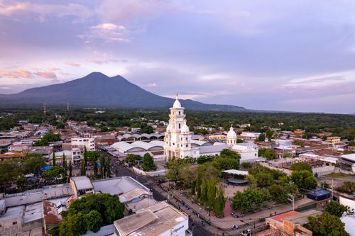 Free Stunning aerial view of Zacatecoluca showcasing a church with a volcanic backdrop under a morning sky. Stock Photo