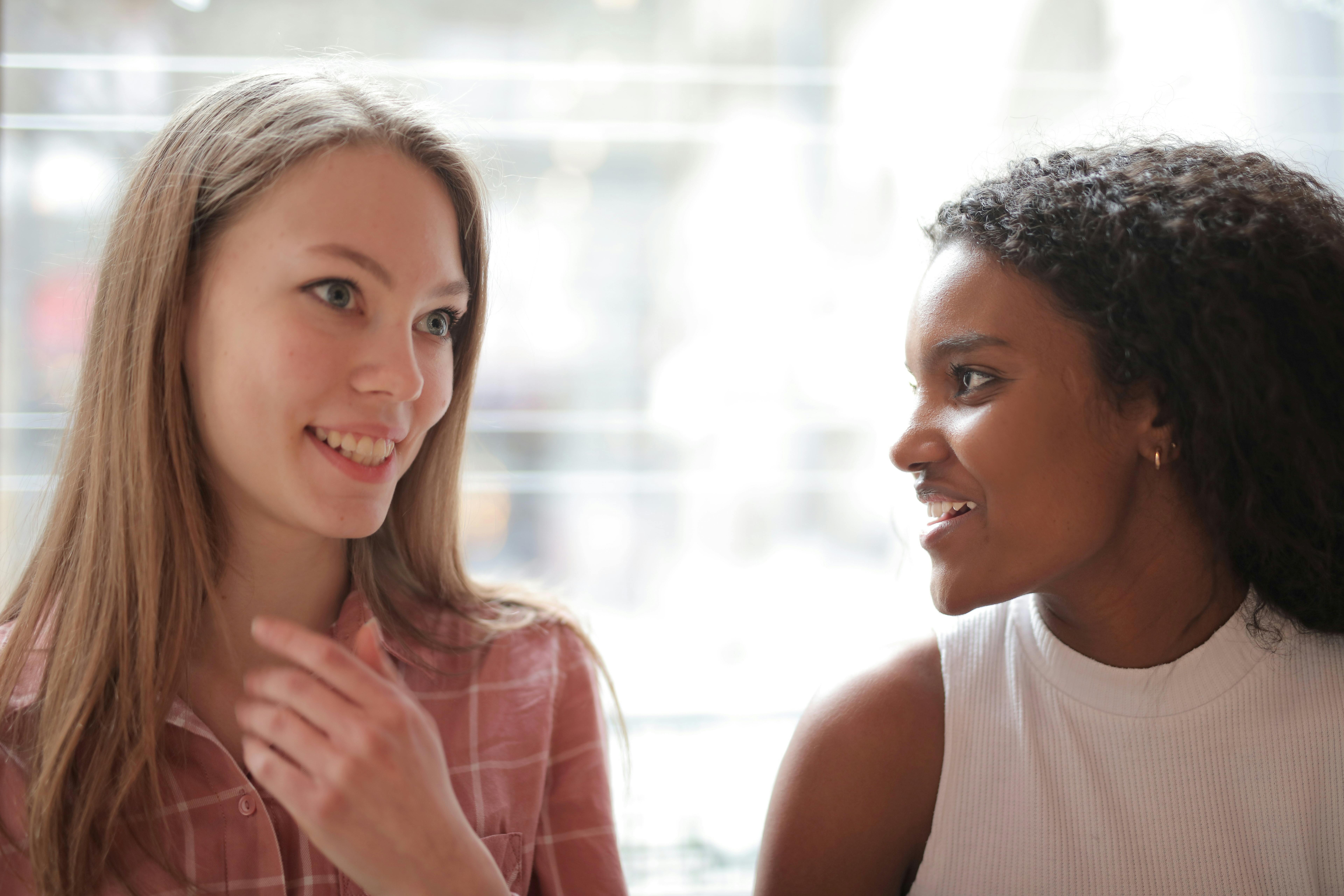 woman in white tank top beside woman in pink and white stripe shirt