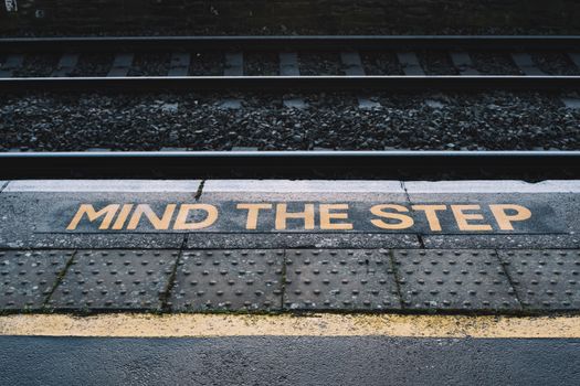 Metal platform with yellow inscription marking near railroad on city street in daytime