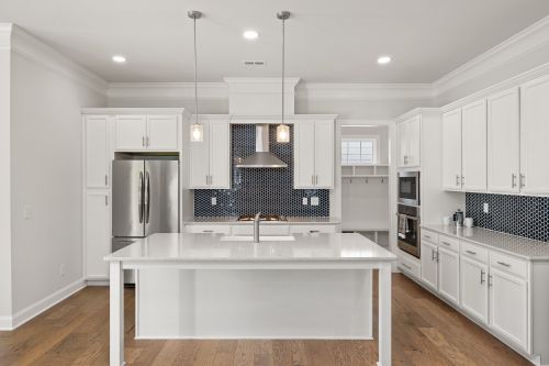 Free Elegant modern kitchen featuring white cabinetry, central island, wooden flooring, and stainless steel appliances. Stock Photo