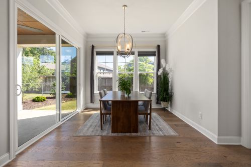Free Bright dining room interior featuring a wooden table, modern chandelier, and garden view through large windows. Stock Photo