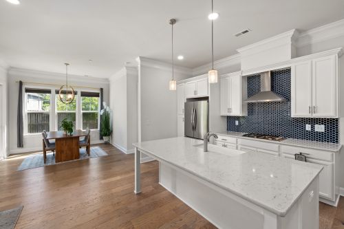 Free Stylish kitchen with white cabinets, marble island, and spacious dining area. Stock Photo
