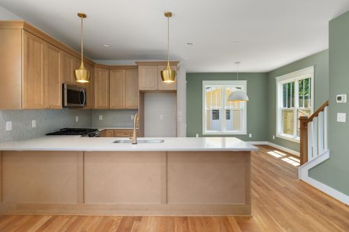 Free Bright and spacious kitchen with wood cabinets and modern fixtures, featuring natural lighting. Stock Photo