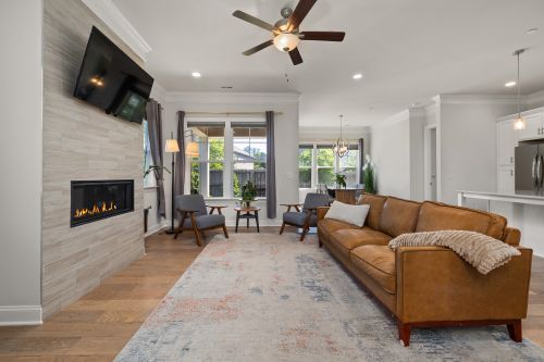 Free Stylish living room featuring a modern sofa, fireplace, and large windows. Stock Photo