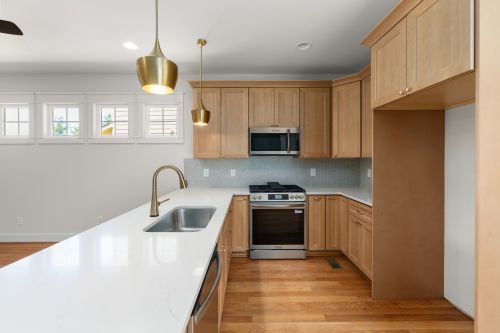 Free Spacious modern kitchen featuring wooden cabinets, stainless steel appliances, and stylish pendant lighting. Stock Photo